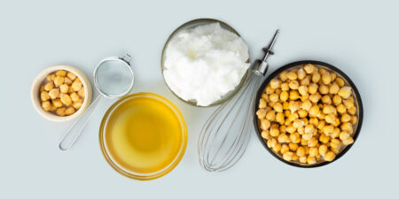 Chickpea aquafaba. Egg replacement. Vegan cooking concept. Whipped chickpeas liquid in glass bowl. chickpea in a ceramic plate. whisk. gray isolated background. Vegan egg replacement ingredient.